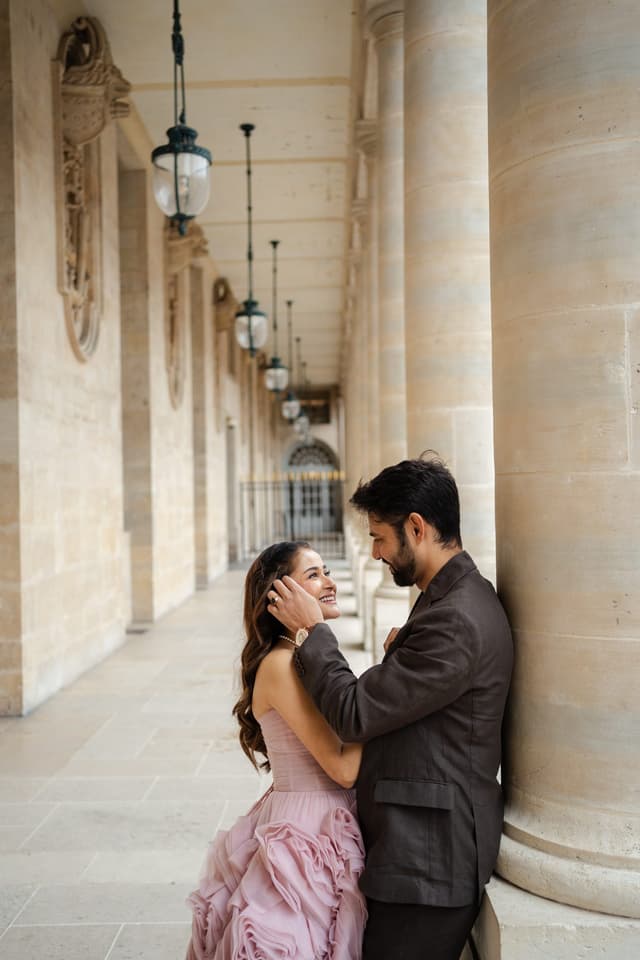 Couple leaning against a stone column at Palais Royal during a romantic portrait photoshoot in Paris