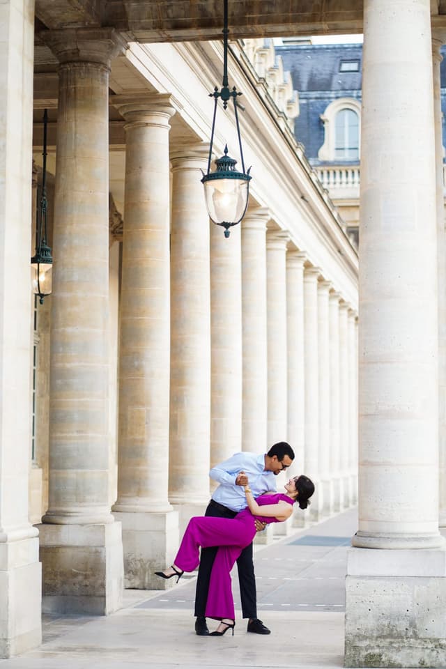 Playful couple doing a dip pose between the historic pillars of Palais Royal during a Paris couple photo session.