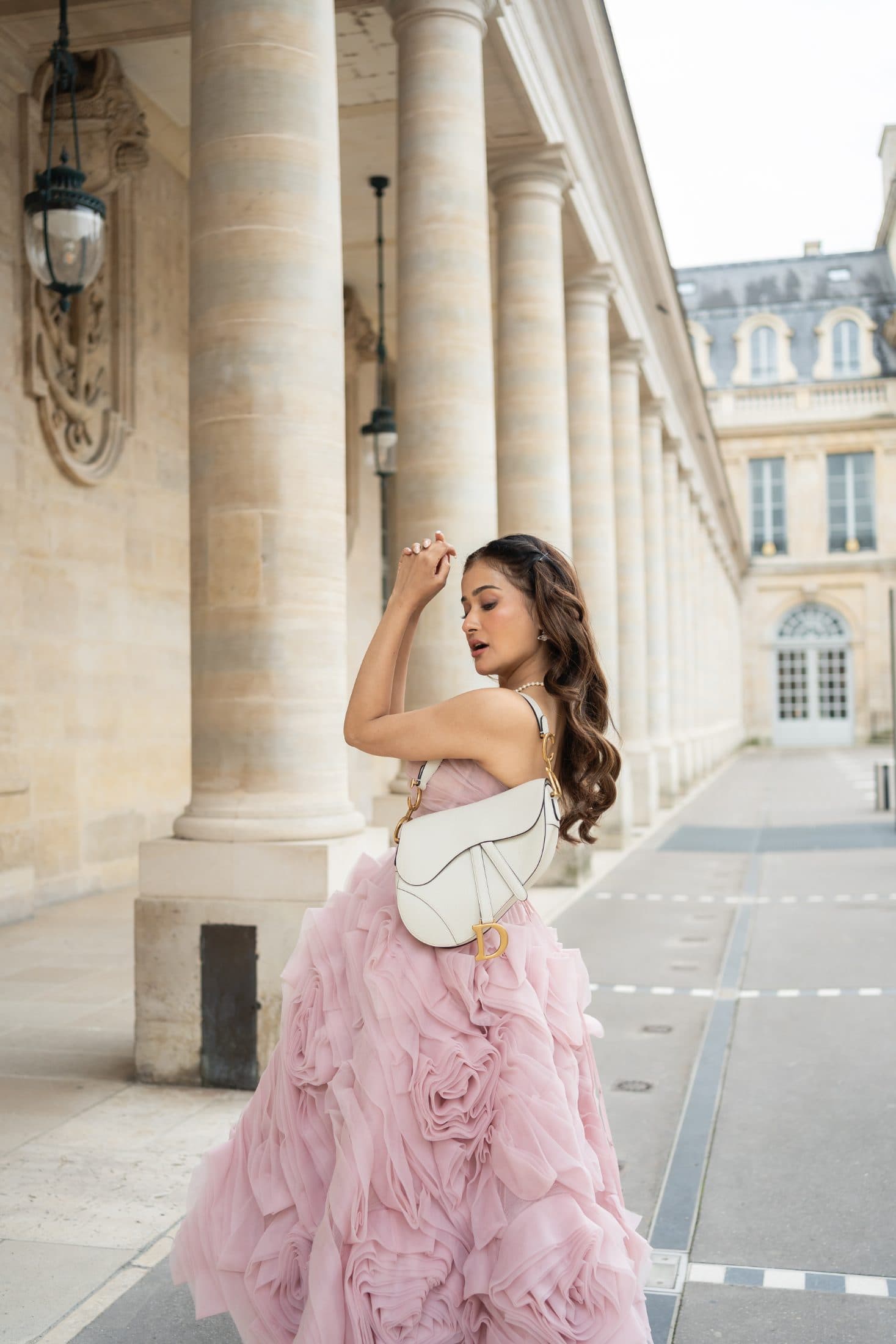 Female traveler in a pink ruffled gown posing at Palais Royal during a solo photo session in Paris.