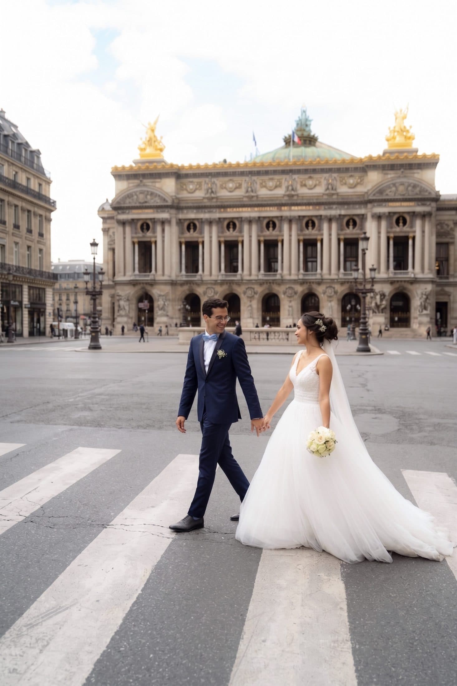 Bride and groom holding hands while crossing the street near Palais Garnier Opera House during a Paris wedding photo session.